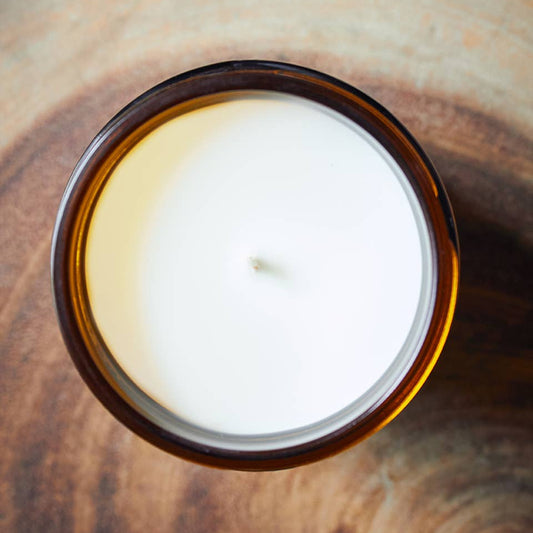 Candle in a glass container on a wooden surface
