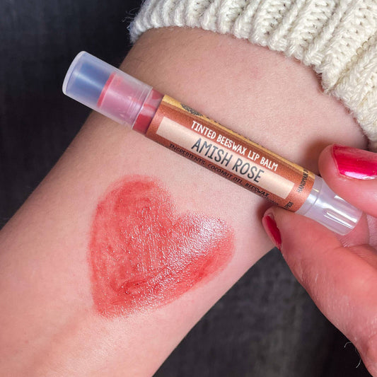 Lip balm with a heart-shaped swatch of color on a wrist