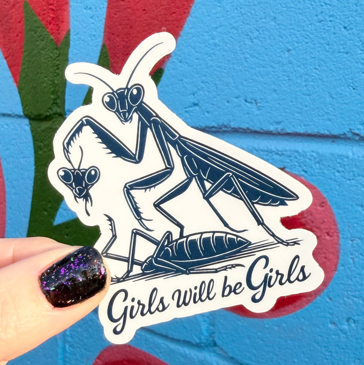 Sticker with a praying mantis design and 'Girls Will be Girls' text on a colorful background.