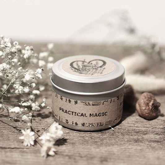 Small cylindrical container labeled 'Practical Magic' on a wooden surface with flowers.