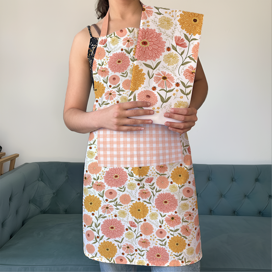 Person wearing a floral apron with a matching patterned bag in a room with a blue couch.