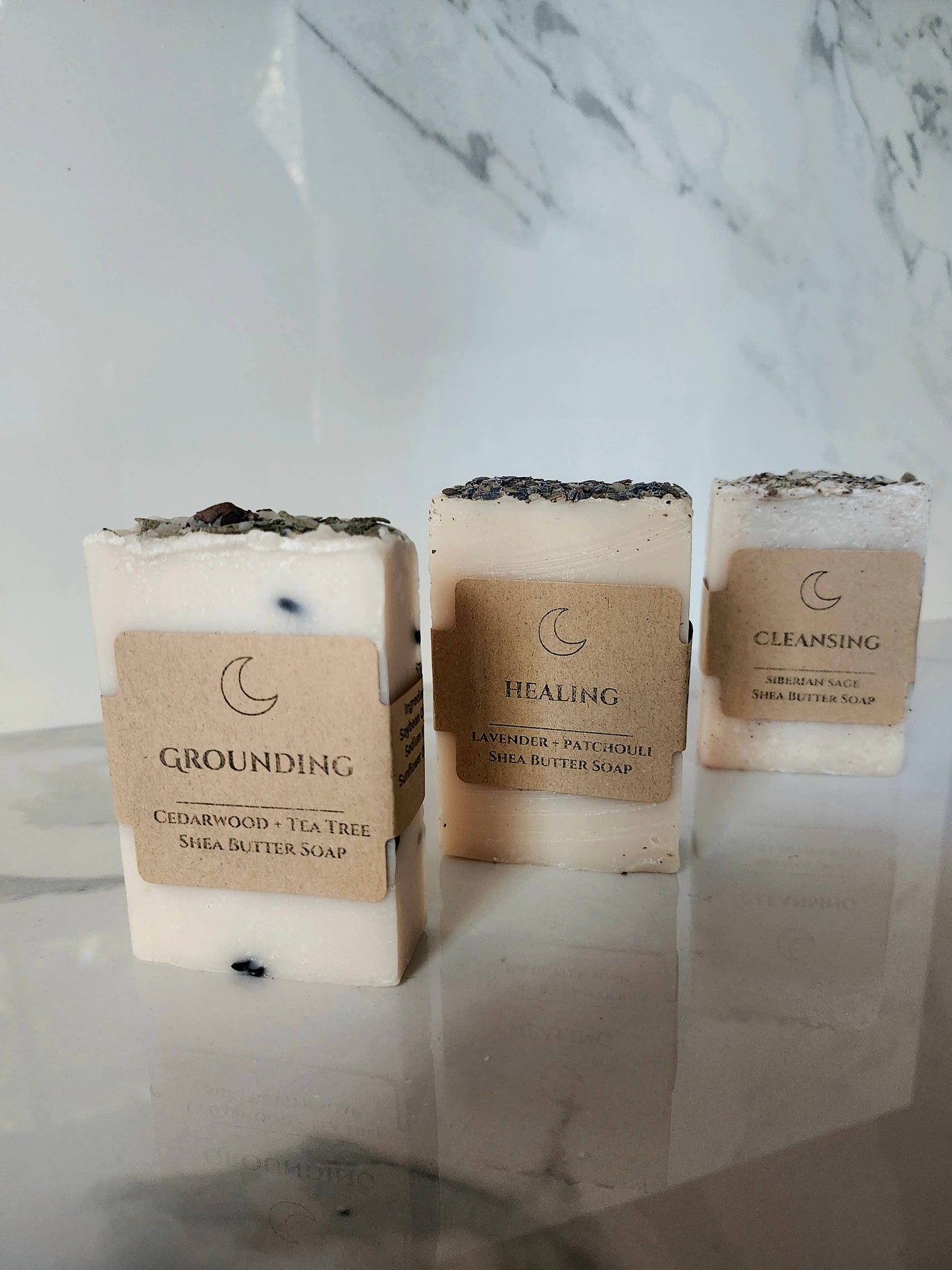 Three bars of soap with labels on a marble surface