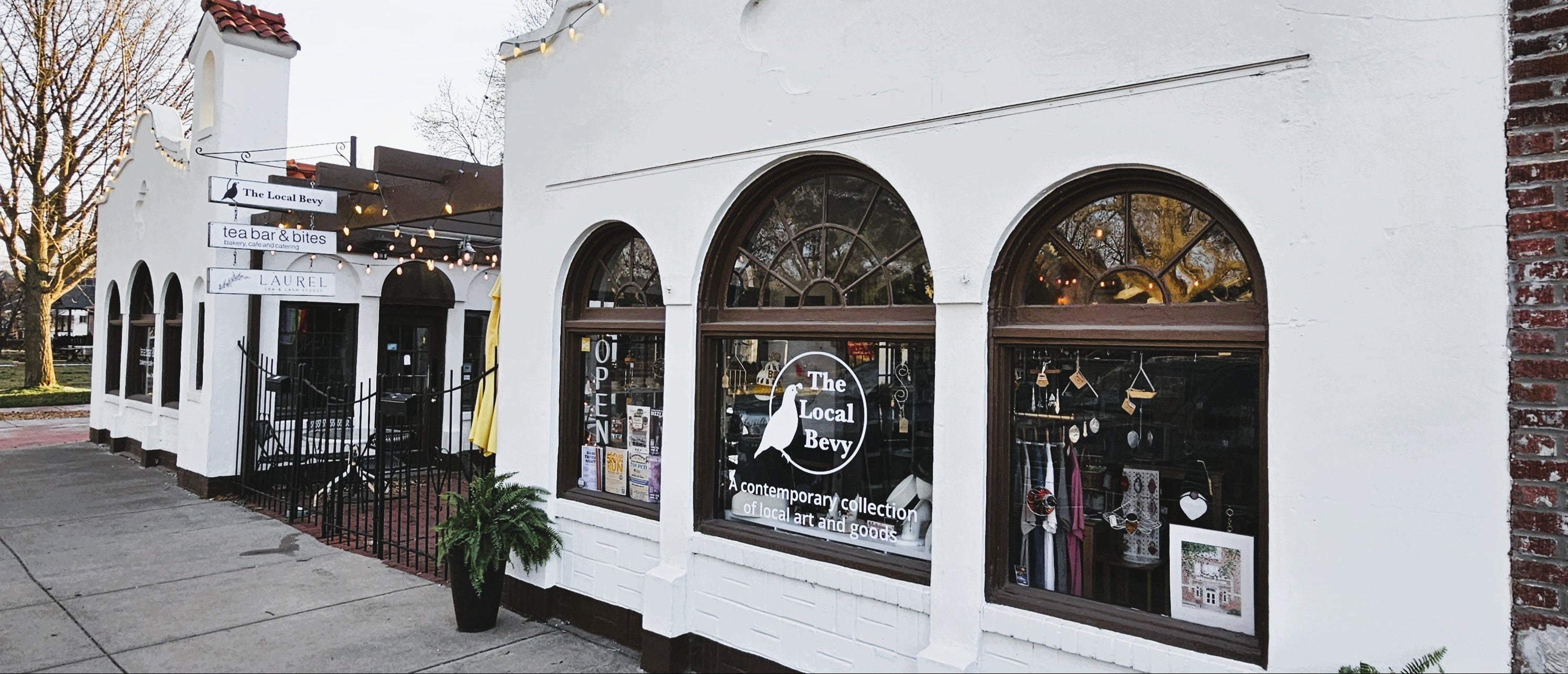 White building with large windows displaying store items and a sign, front of The Local Bevy in Springfield MO