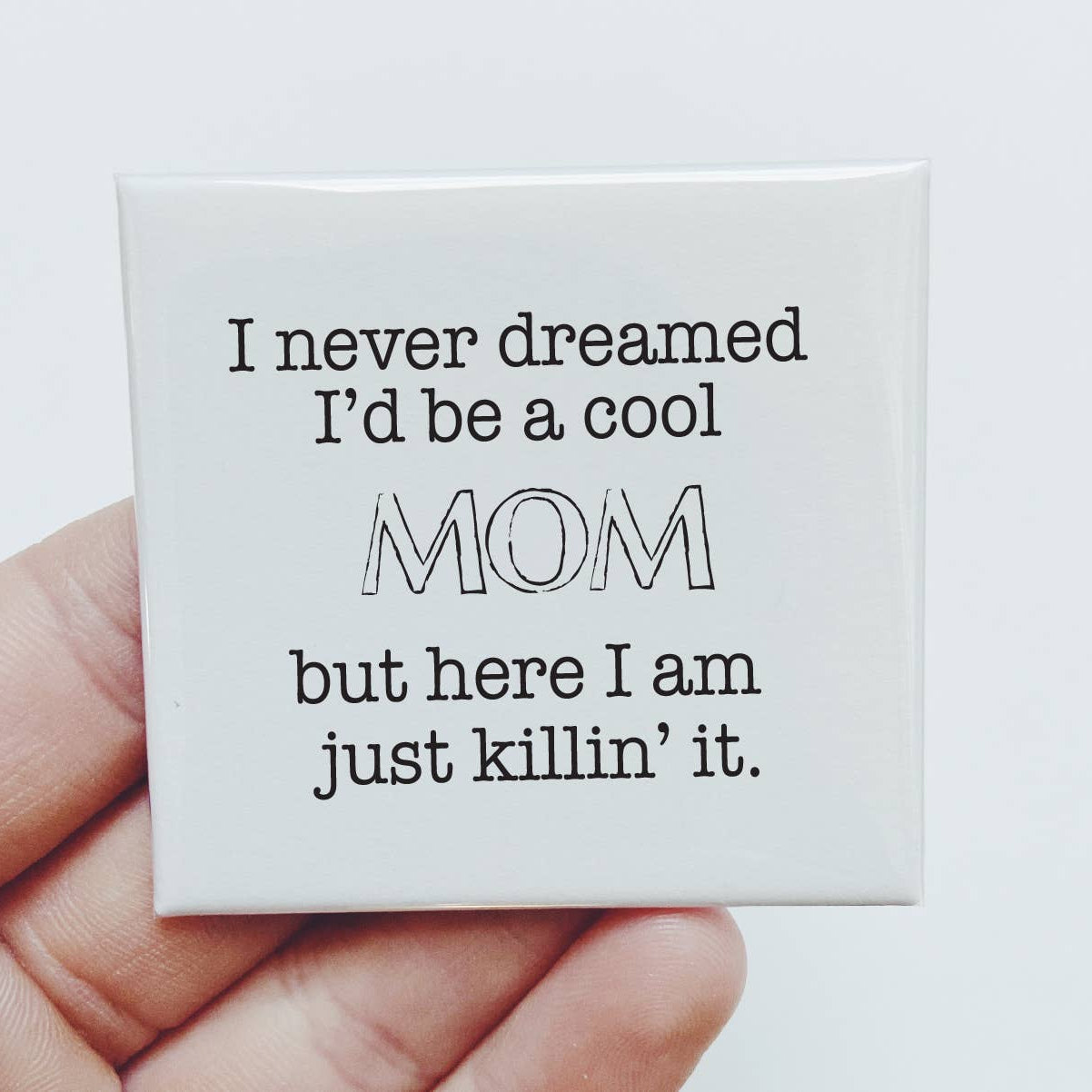 Small white card with humorous text held by a hand against a light background