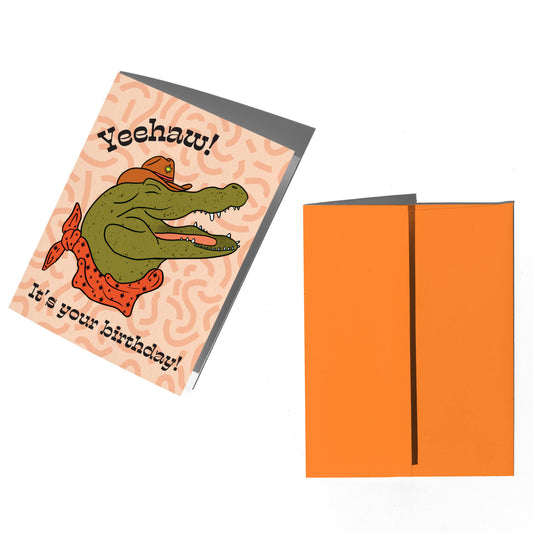 Birthday card with alligator illustration and orange envelope on a white background