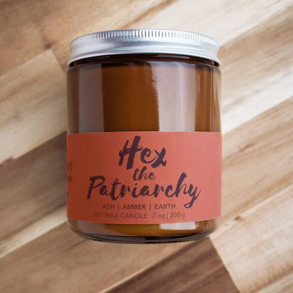 Candle jar with 'Hex the Patriarchy' label on a wooden surface