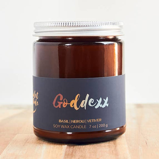 Candle jar labeled 'Goddess' on a wooden surface with a white background