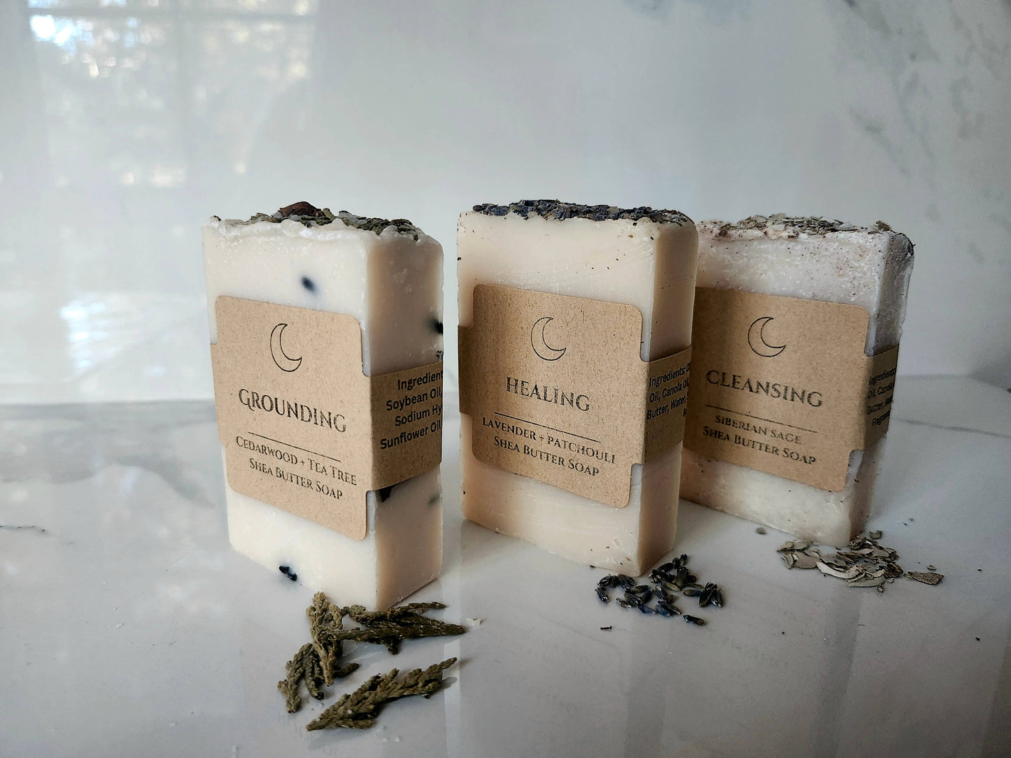 Three bars of soap with labels on a white surface with a blurred background