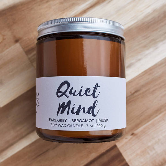 Candle jar labeled 'Quiet Mind' on a wooden surface