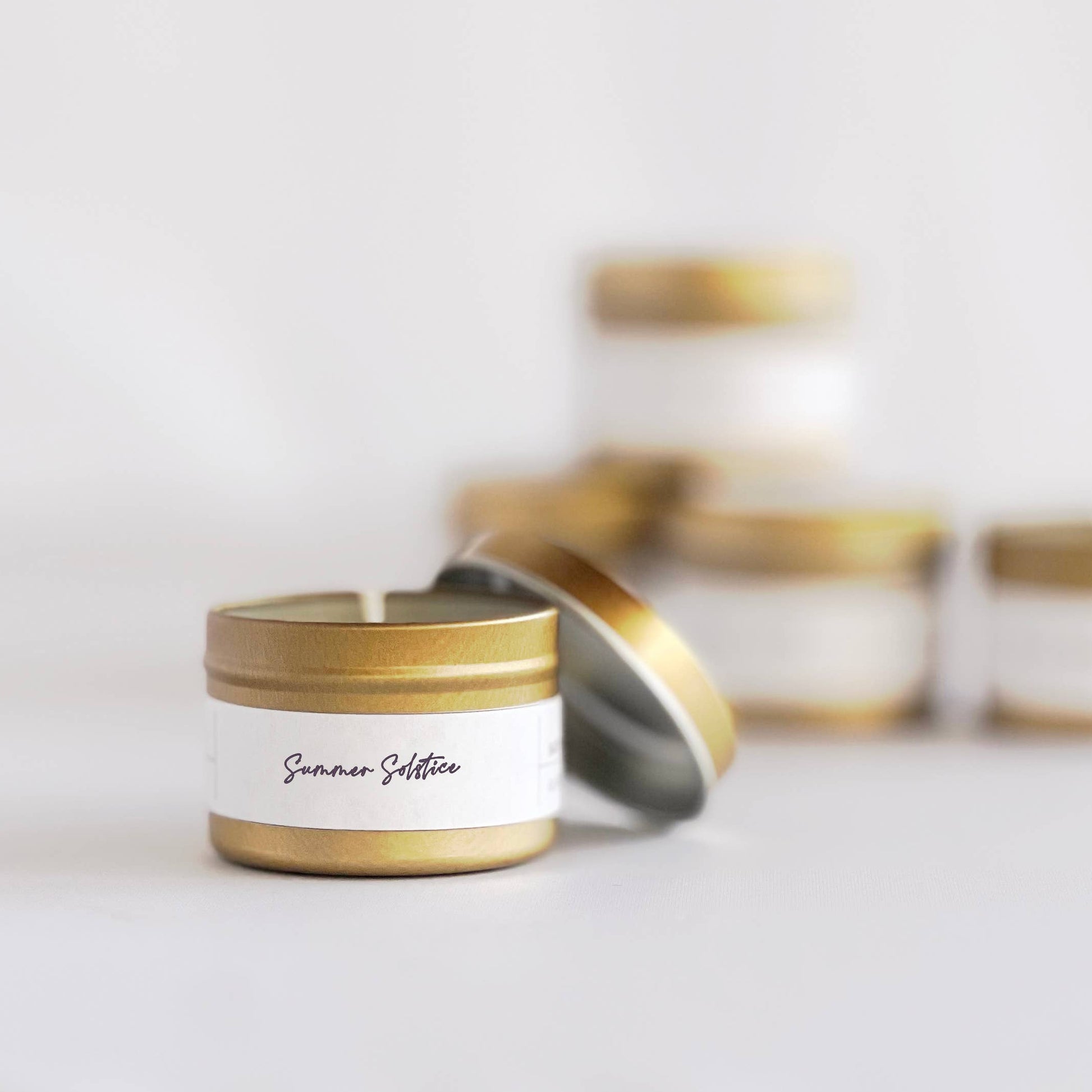 Candle with gold lid and white label on a light background