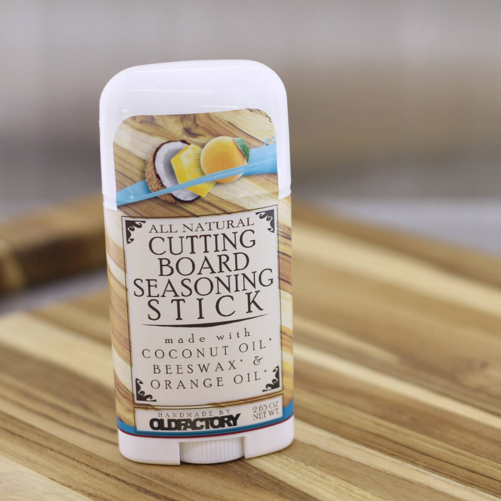 A single stick of Old Factory All Natural Cutting Board Seasoning Stick standing upright on a wooden surface with a softly blurred neutral background.