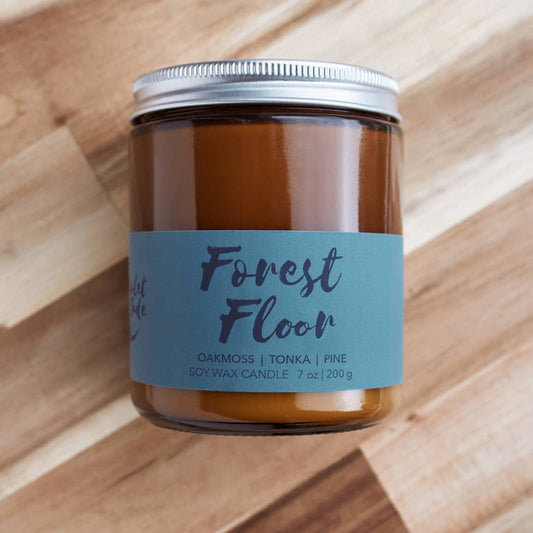 Candle jar labeled 'Forest Floor' on a wooden surface