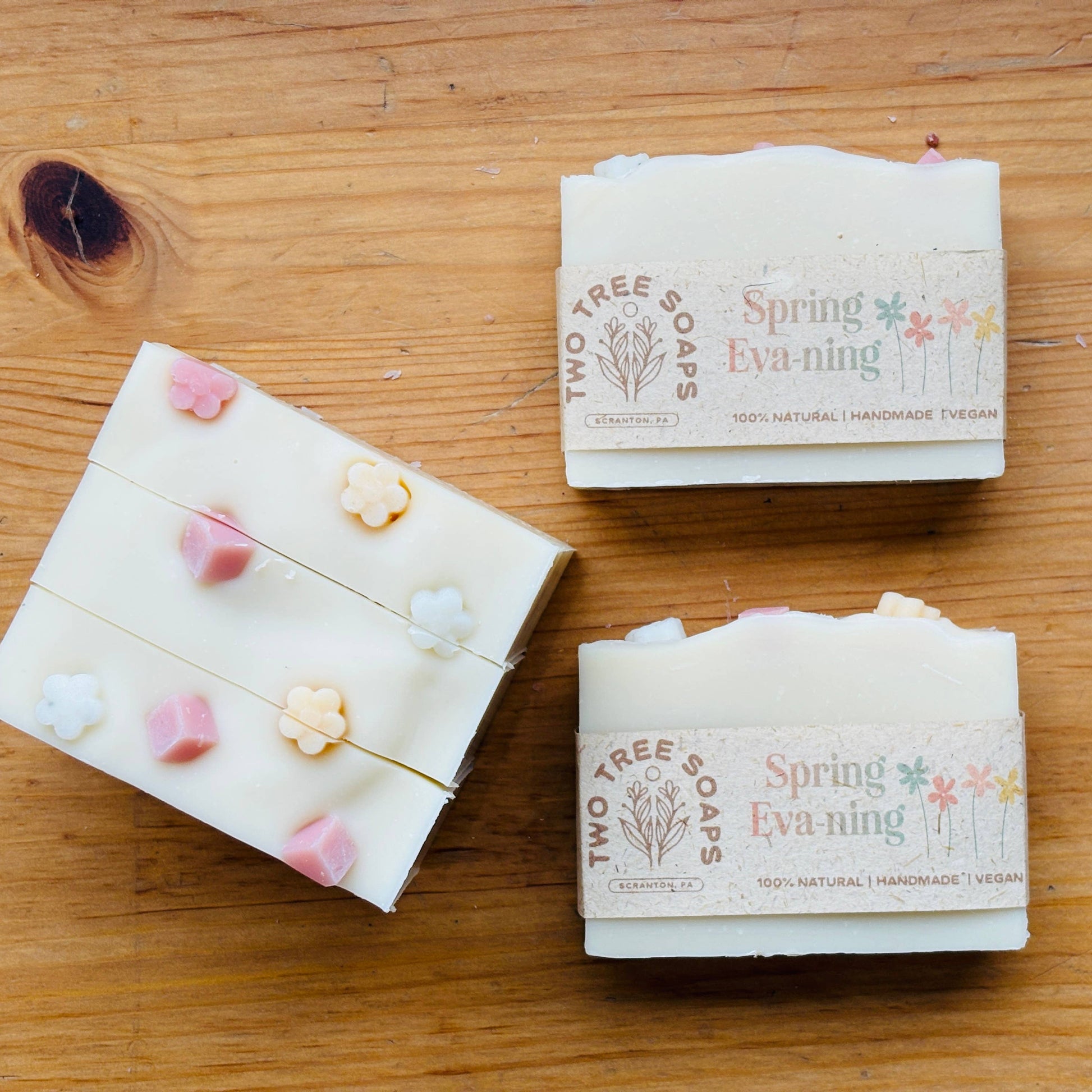 Two bars of soap with 'Spring Evening' branding on a wooden surface