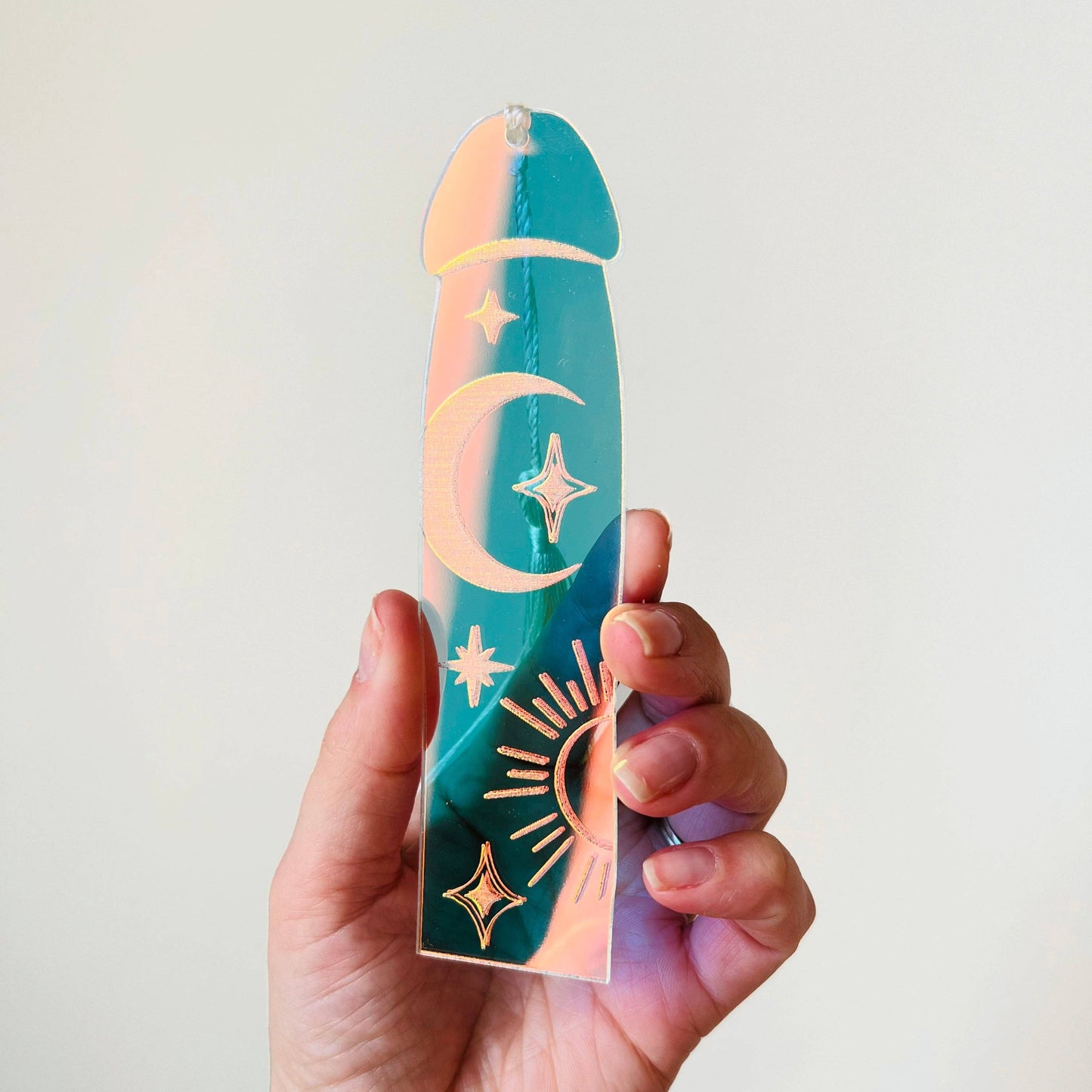 Hand holding a colorful object with celestial designs against a plain background