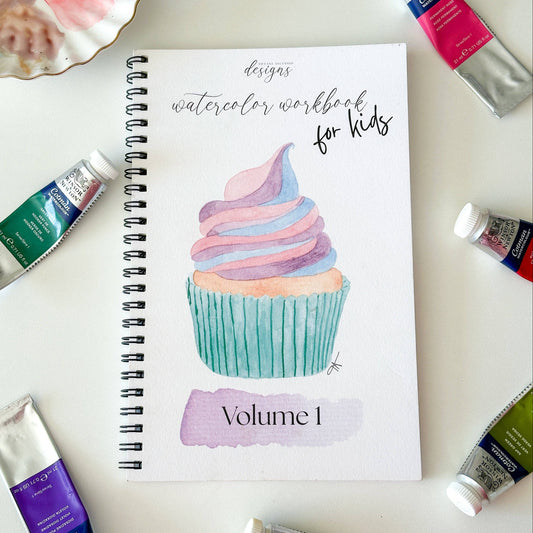 Watercolor workbook for kids with paint tubes on a white surface
