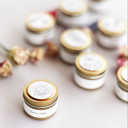 Small jars with gold lids on a light surface with flowers in the background