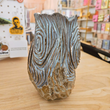 Decorative vase with wavy pattern on a wooden surface in a store setting