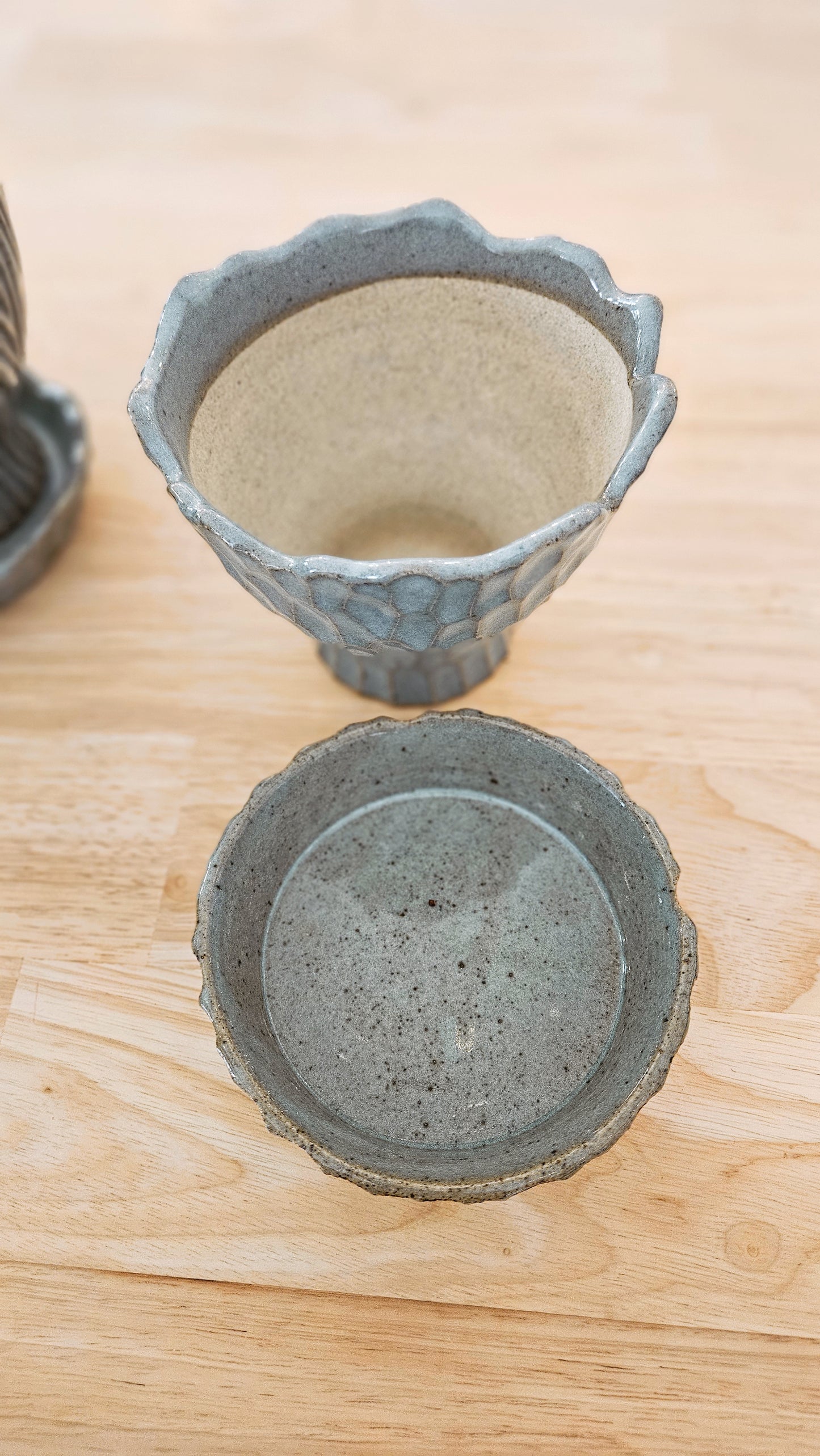 Two ceramic planters with textured surfaces on a wooden surface