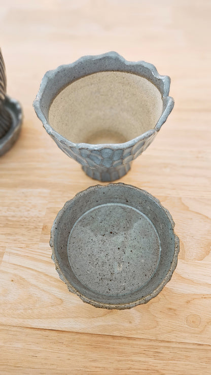 Two ceramic planters with textured surfaces on a wooden surface