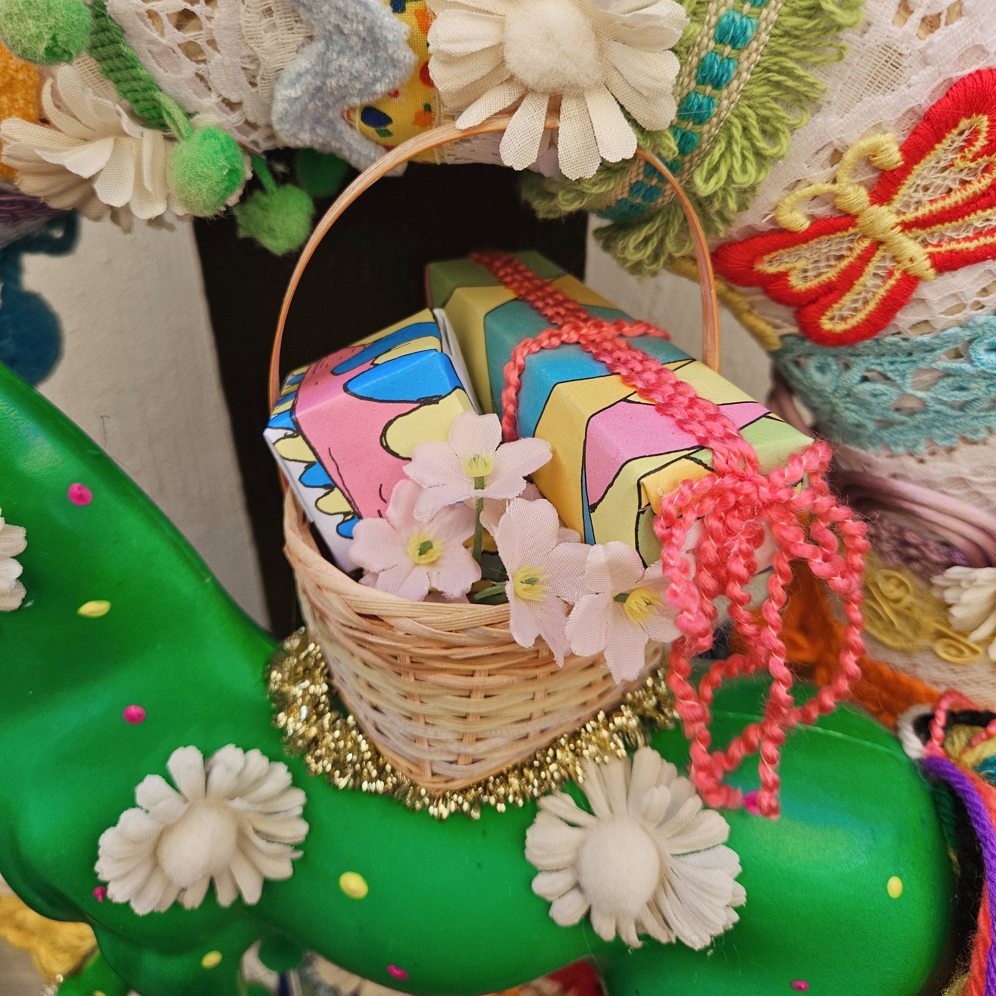 Colorful decorative item with a basket, flowers, and ribbons on a green background