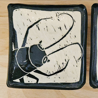 Set of three ceramic trays with abstract black designs on a wooden surface