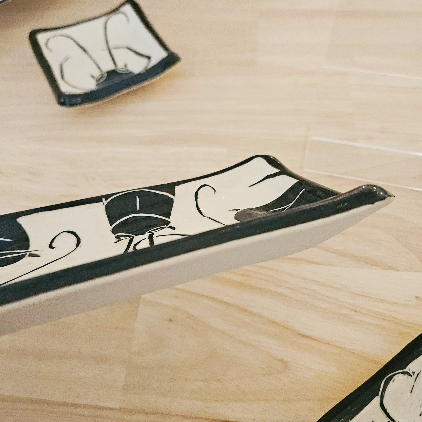 Decorative ceramic trays with black and white patterns on a wooden surface