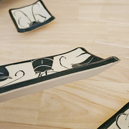 Decorative ceramic trays with black and white patterns on a wooden surface