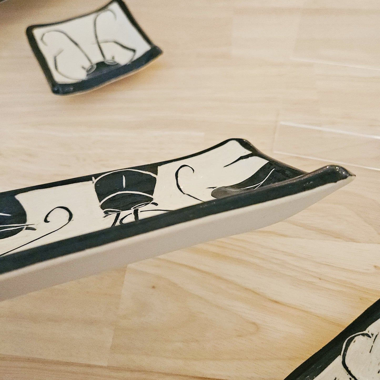 Decorative ceramic trays with black and white patterns on a wooden surface