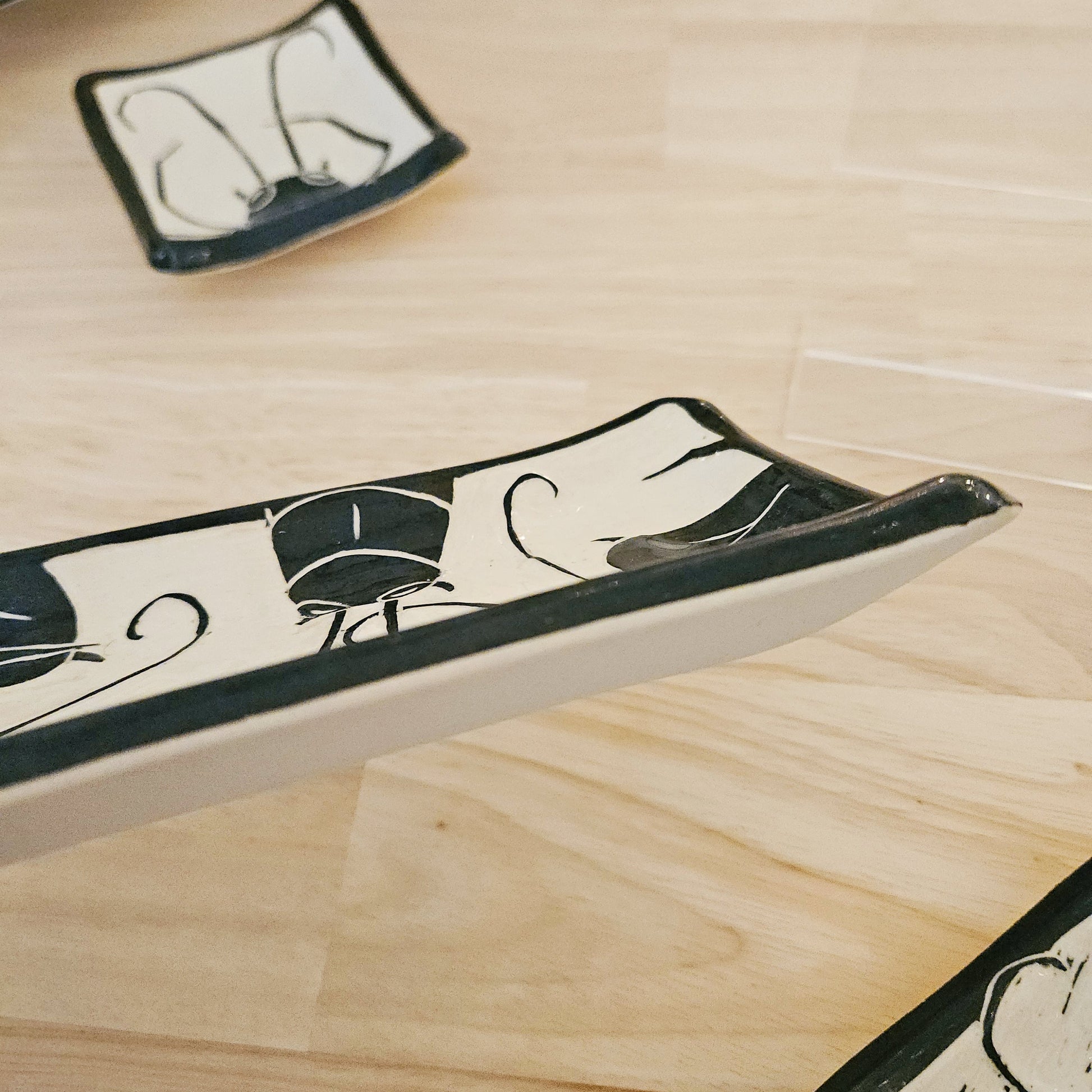 Decorative ceramic trays with black and white patterns on a wooden surface