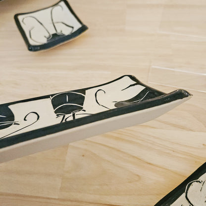 Decorative ceramic trays with black and white patterns on a wooden surface