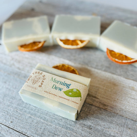 Bar of soap with 'Morning Dew' branding on a wooden surface with dried oranges.