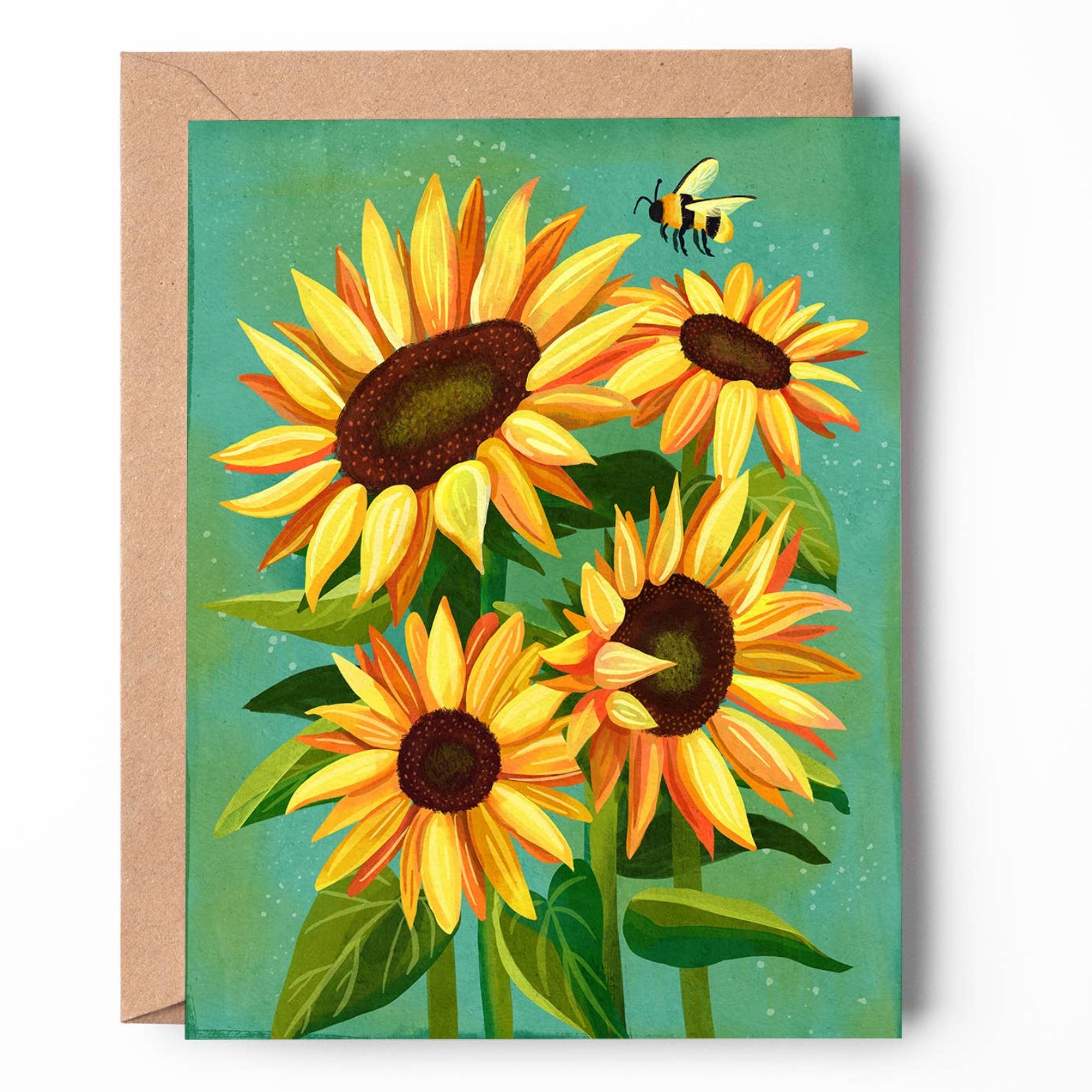 A square greeting card featuring a colorful illustration of four sunflowers and a small bumblebee on a teal background, shown with a brown kraft envelope behind it on a white studio background.