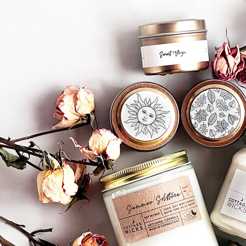 Candles with decorative labels and floral elements on a light background
