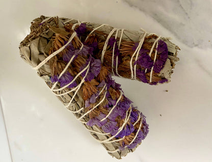 Two bundles of sage and purple flowers tied together on a white surface