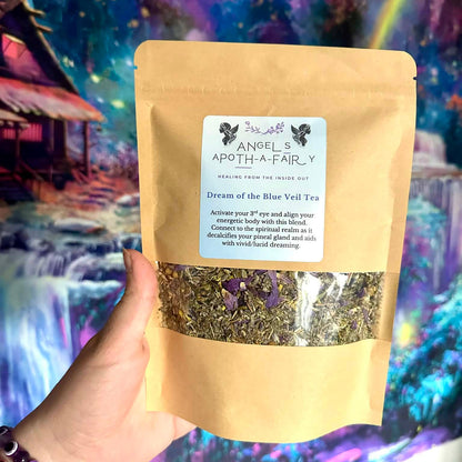 Bag of 'Dream of the Blue Veil Tea' from 'Angel's Apothecary' held in front of a colorful, fantasy-themed background.