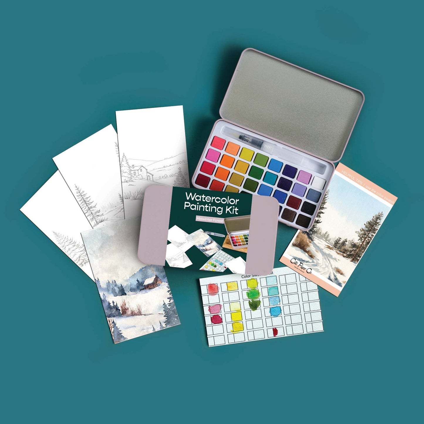 A watercolor painting kit arranged on a teal background, including a metal tin of watercolor pans, a green booklet, practice sheets, paint tubes, and a small scenic card.