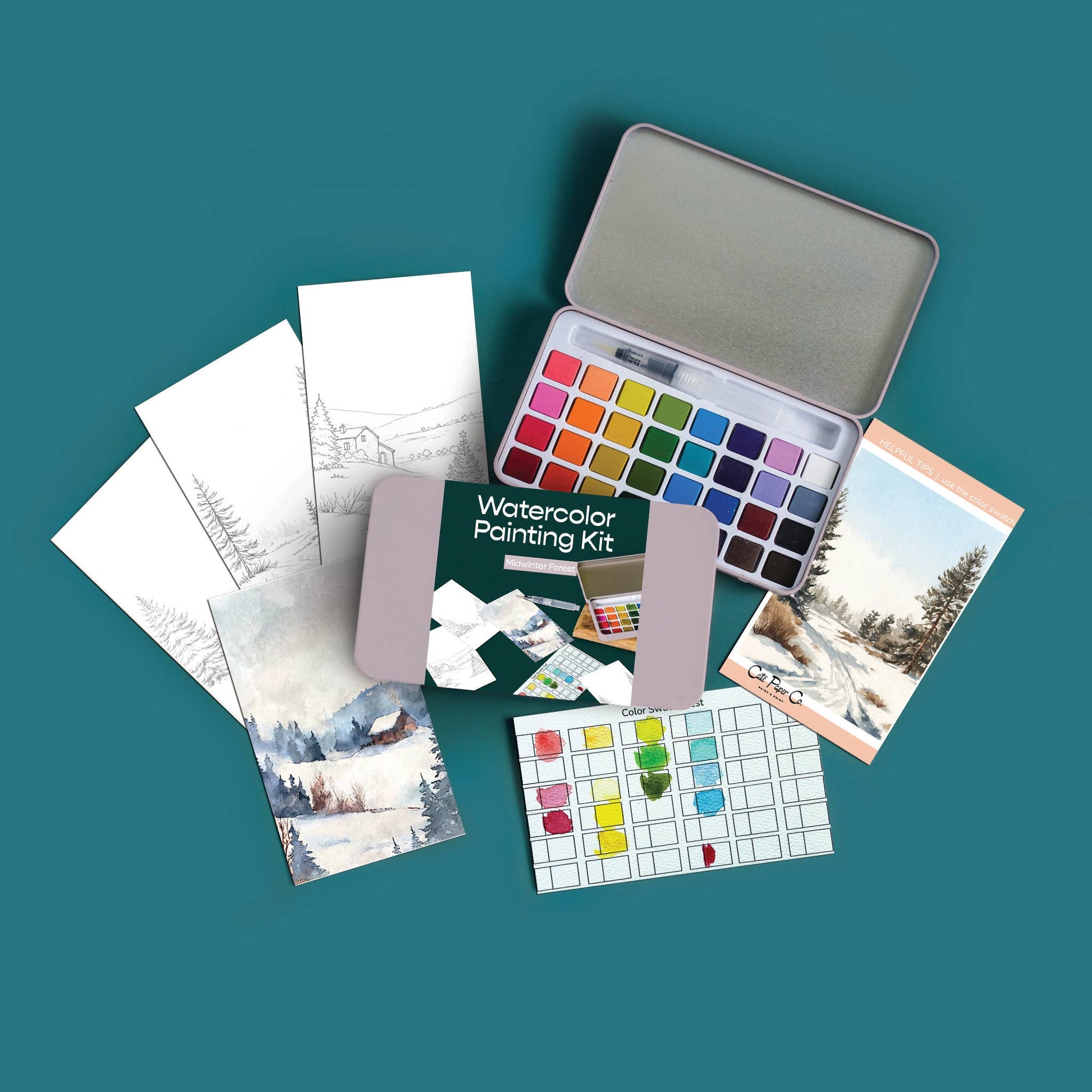 A watercolor painting kit arranged on a teal background, including a metal tin of watercolor pans, a green booklet, practice sheets, paint tubes, and a small scenic card.