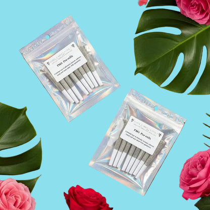 Two packages of dental floss on a wooden surface with pink and red flowers and green leaves.