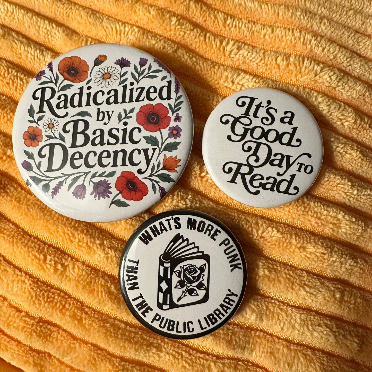 Three buttons with motivational phrases on a textured yellow fabric background