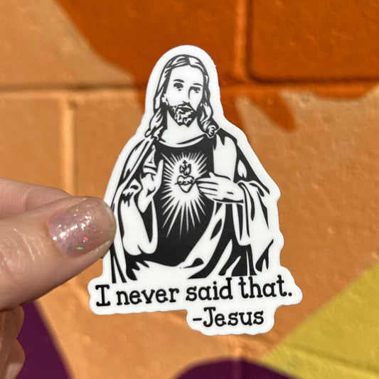 Sticker of a religious figure with text held by a hand against a colorful background