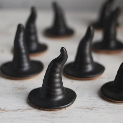 Black ceramic witch hats on a wooden surface