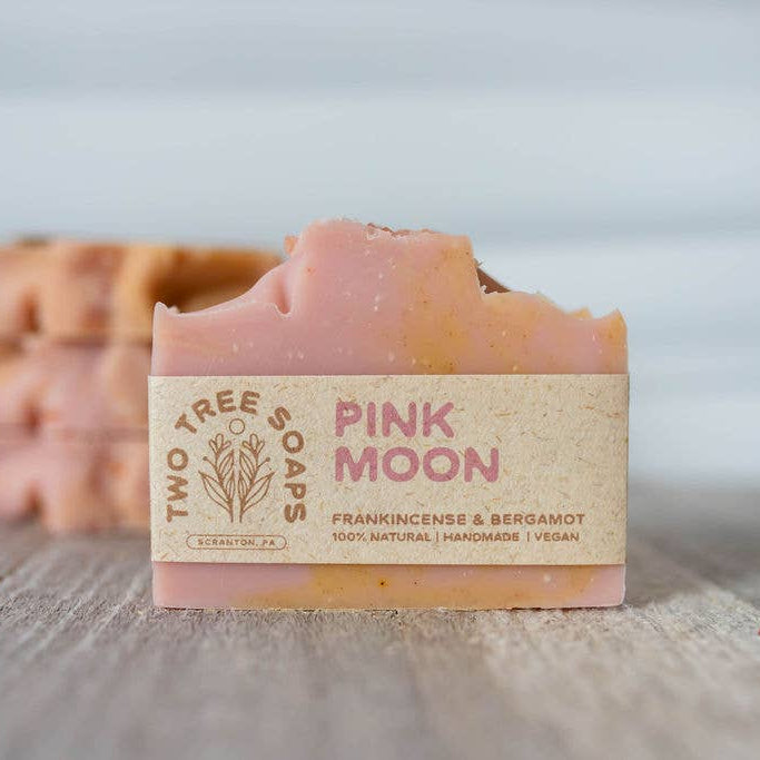 Bar of soap with 'Pink Moon' label from Two Tree Soaps on a wooden surface.