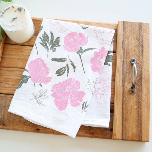 Floral towel on a wooden tray with a candle