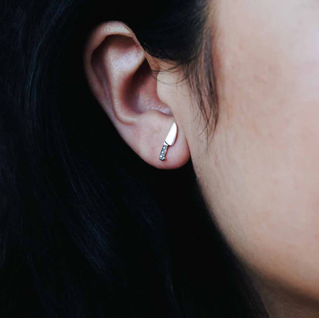 Close-up of an ear wearing a small earring with a dark background
