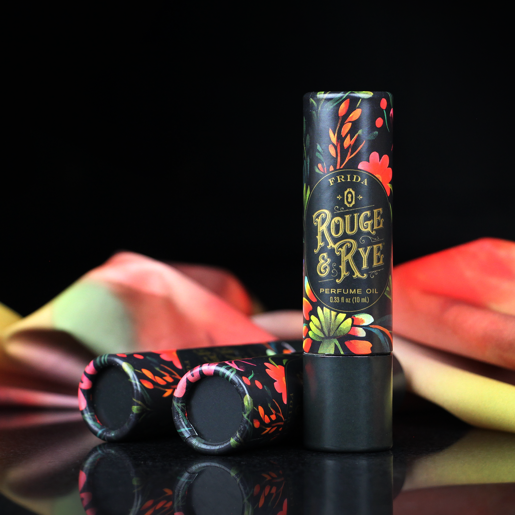 Perfume oil bottle with colorful packaging on a reflective surface with a black background