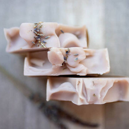 Three bars of soap with lavender buds on a wooden surface
