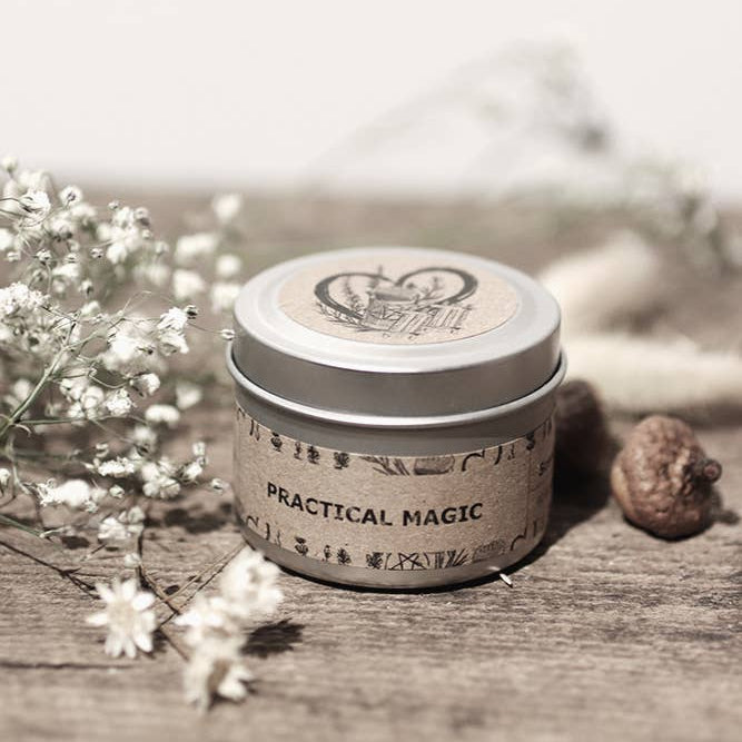 Small cylindrical container labeled 'Practical Magic' on a wooden surface with flowers.