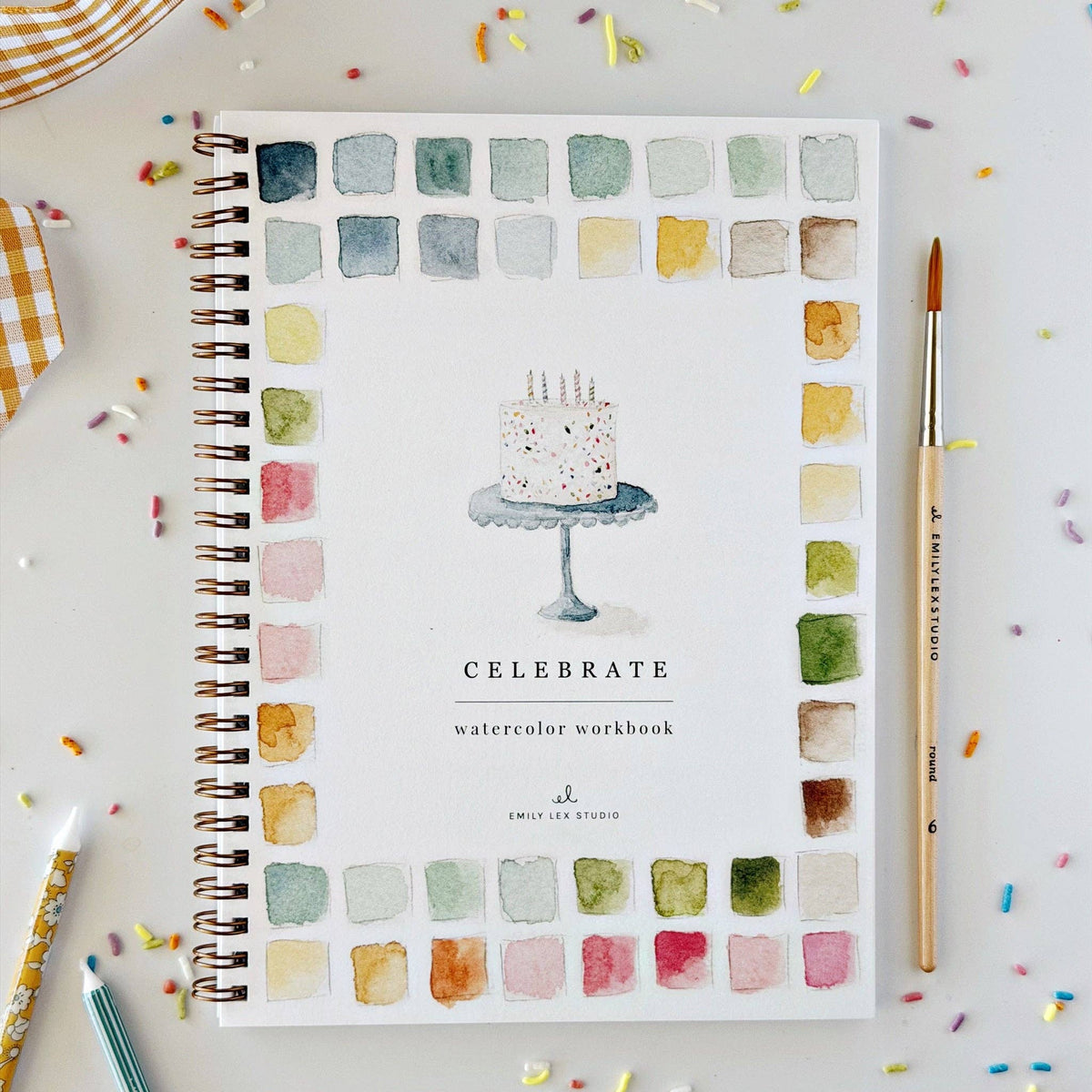 Watercolor workbook titled 'Celebrate' with a cake illustration on a colorful background