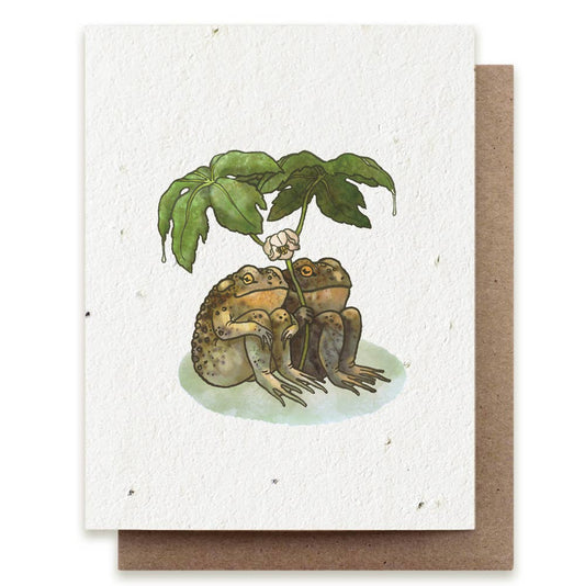 Greeting card with illustration of two frogs under a leaf, on a white background.