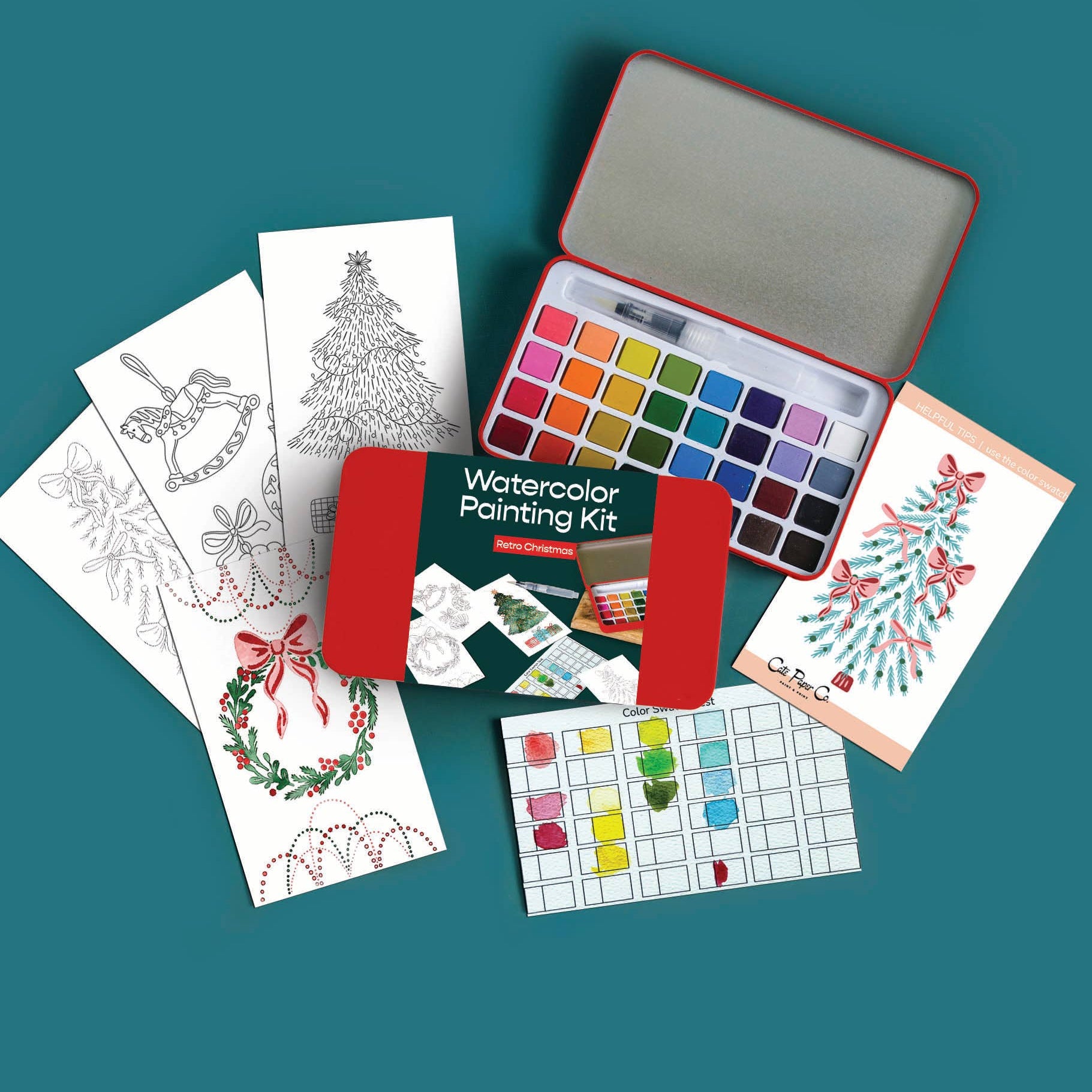 A watercolor painting kit arranged on a teal background, including an open red metal case with multiple paint wells, several printed coloring/illustration cards, a green booklet, and a small palette sheet.
